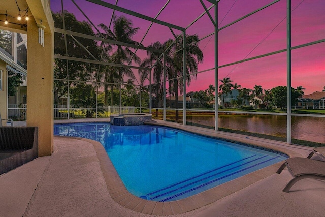 pool at dusk featuring glass enclosure, a patio area, a water view, and an in ground hot tub