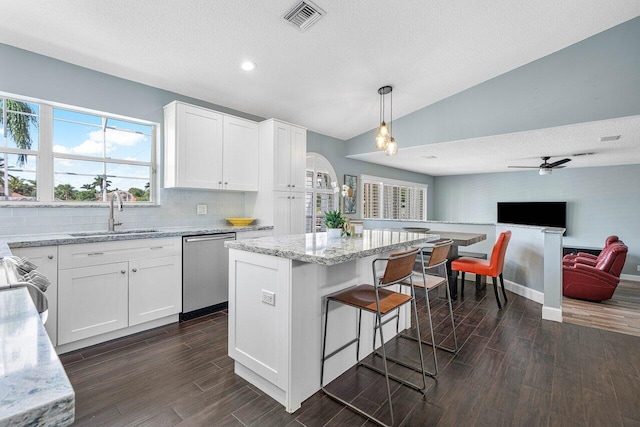 kitchen featuring light stone counters, wood finish floors, stainless steel dishwasher, open floor plan, and a sink