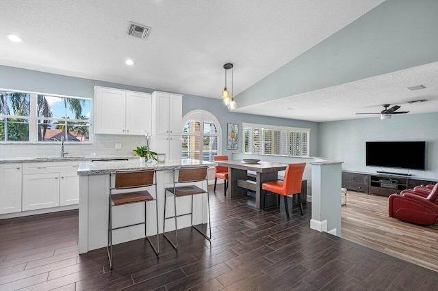 kitchen with a textured ceiling, dark wood-type flooring, sink, decorative light fixtures, and white cabinetry