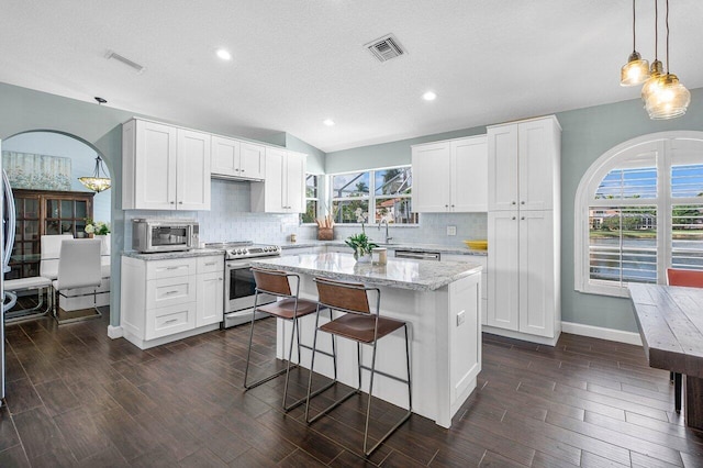 kitchen featuring appliances with stainless steel finishes, a center island, white cabinetry, and a wealth of natural light