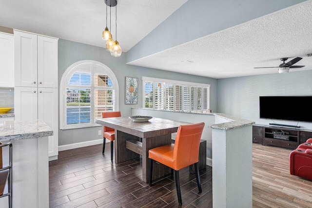 dining room with hardwood / wood-style floors, a textured ceiling, vaulted ceiling, and ceiling fan