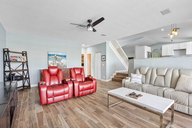 living room featuring ceiling fan, light wood-type flooring, a textured ceiling, and vaulted ceiling