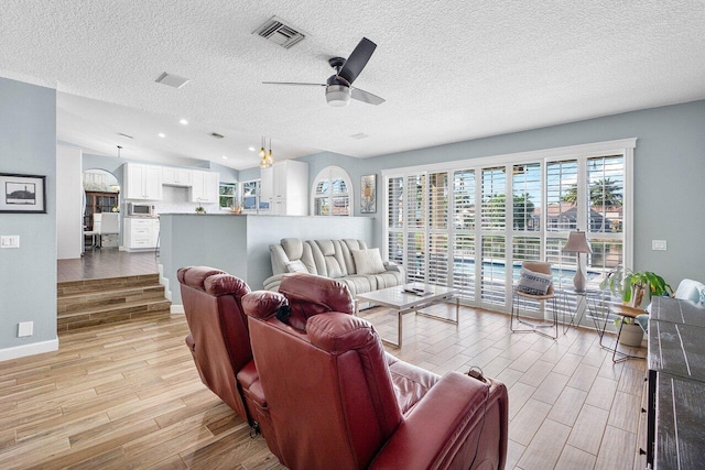 living room with light wood-type flooring, a textured ceiling, and vaulted ceiling