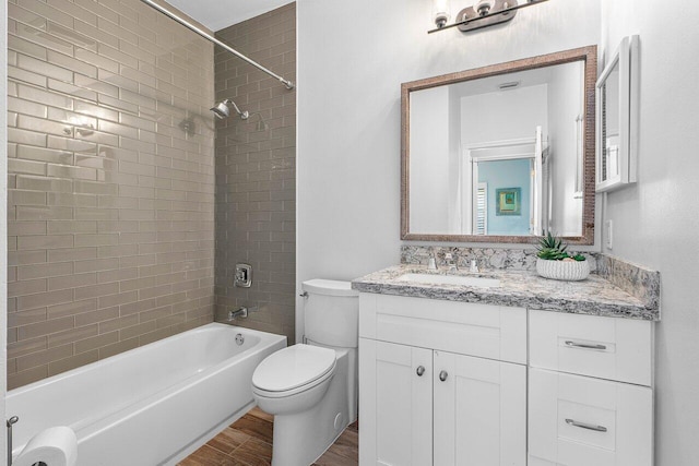 full bathroom with tiled shower / bath combo, toilet, wood-type flooring, and vanity