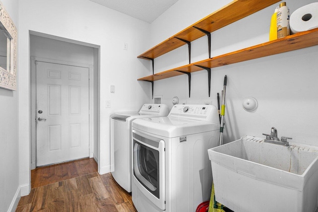 laundry area with a textured ceiling, dark hardwood / wood-style flooring, independent washer and dryer, and sink