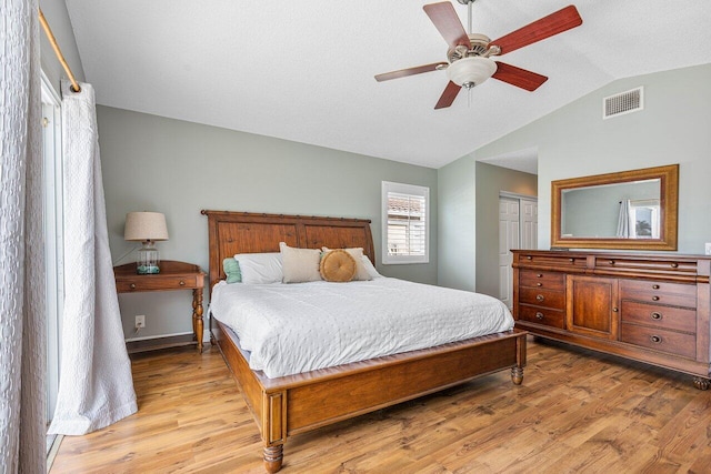 bedroom with ceiling fan, vaulted ceiling, light wood-type flooring, and a closet