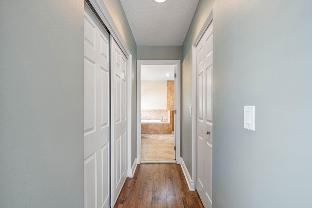 corridor with dark wood-type flooring and a textured ceiling