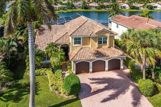 mediterranean / spanish house with a tiled roof, a water view, driveway, and stucco siding