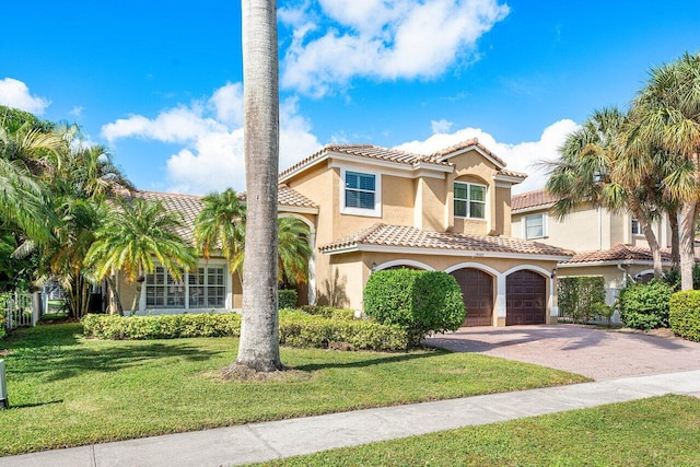 mediterranean / spanish house featuring a garage and a front lawn