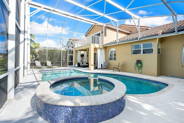 view of pool with a patio area, a pool with connected hot tub, and glass enclosure