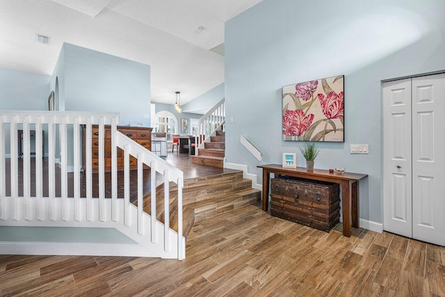 staircase featuring hardwood / wood-style floors, a textured ceiling, and lofted ceiling