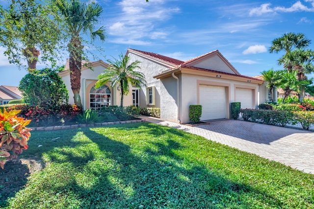 mediterranean / spanish-style home with a front lawn, a tile roof, stucco siding, decorative driveway, and a garage