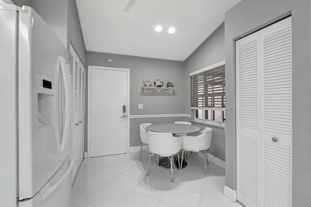 dining space featuring light tile patterned floors and vaulted ceiling