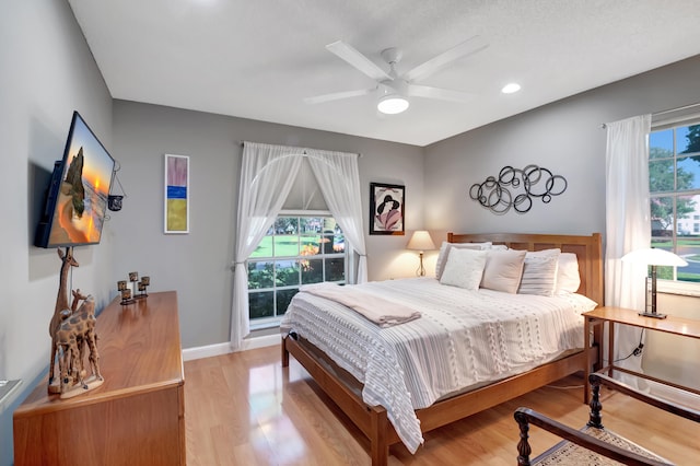 bedroom with ceiling fan, light hardwood / wood-style flooring, and multiple windows