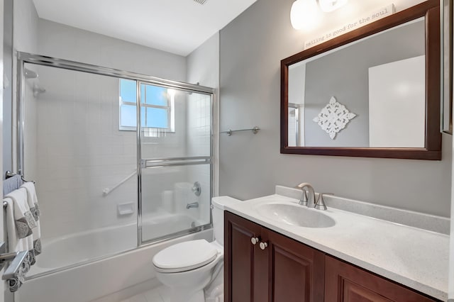 full bathroom with tile patterned floors, vanity, toilet, and bath / shower combo with glass door