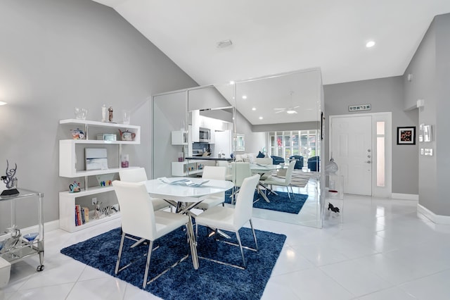 tiled dining space with ceiling fan and high vaulted ceiling