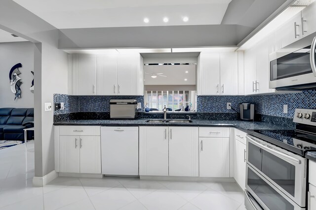 kitchen with sink, stainless steel appliances, light tile patterned floors, decorative backsplash, and white cabinets