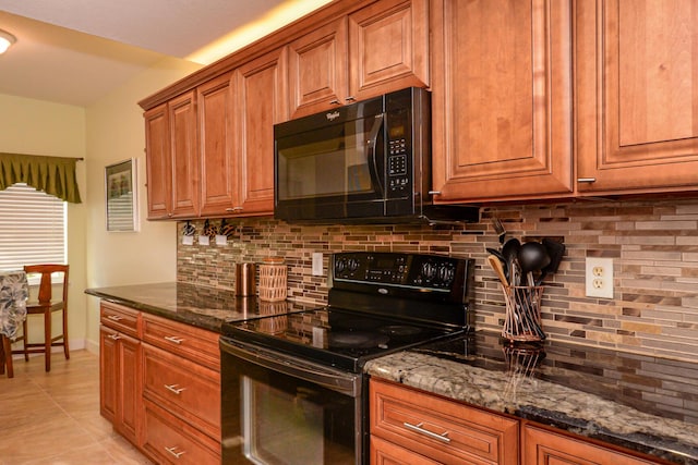 kitchen with dark stone countertops, decorative backsplash, light tile patterned flooring, and black appliances