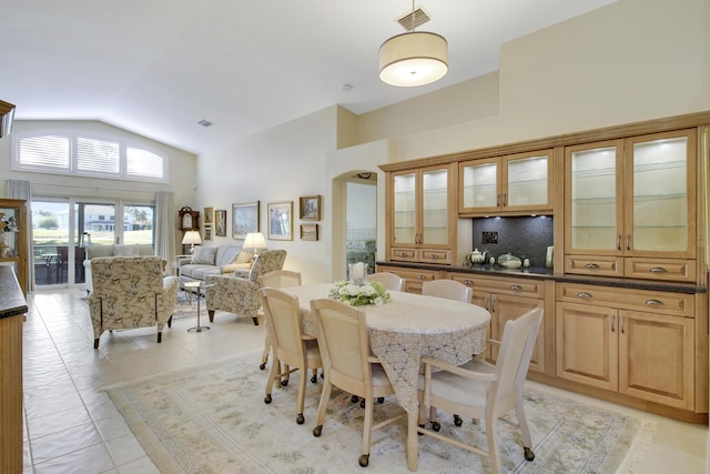 tiled dining space featuring high vaulted ceiling