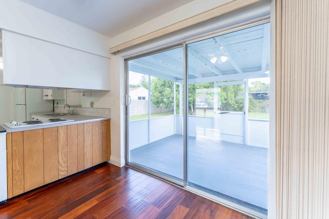 kitchen featuring beam ceiling, white gas stovetop, dark wood-type flooring, and a wealth of natural light