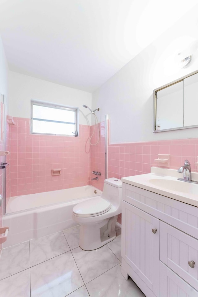 full bathroom featuring vanity, tiled shower / bath, tile patterned flooring, toilet, and tile walls