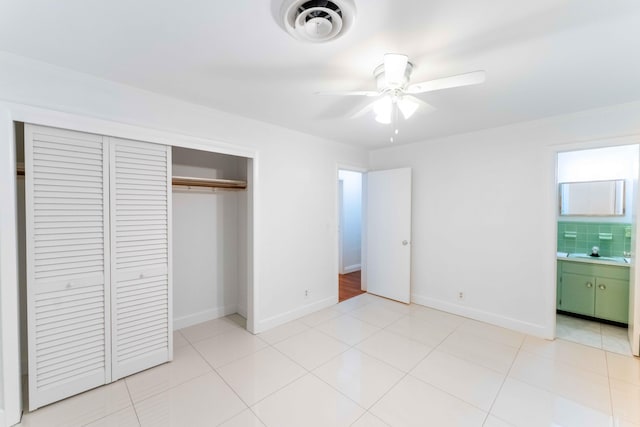 unfurnished bedroom with sink, ensuite bath, ceiling fan, light tile patterned floors, and a closet