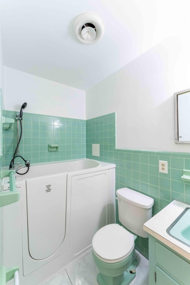 bathroom with vanity, tile patterned floors, toilet, tile walls, and a tub