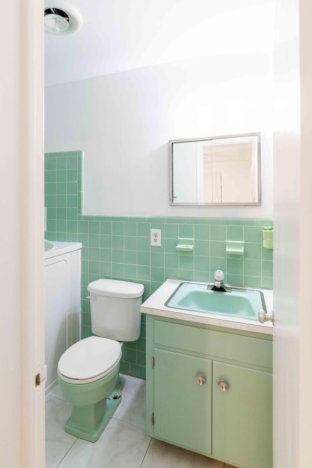 bathroom featuring tile patterned flooring, vanity, tile walls, and toilet