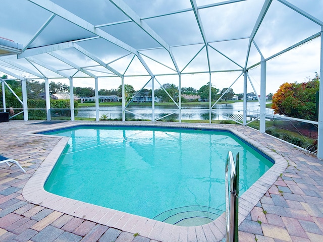 view of swimming pool with a water view, glass enclosure, and a patio area