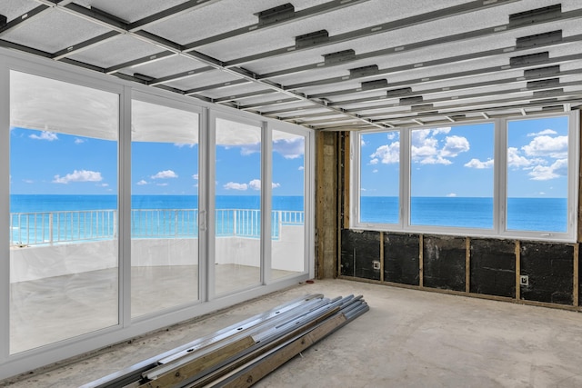 unfurnished sunroom featuring a water view and a beach view