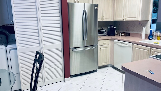 kitchen with dishwasher, stainless steel fridge, independent washer and dryer, light tile patterned floors, and tasteful backsplash