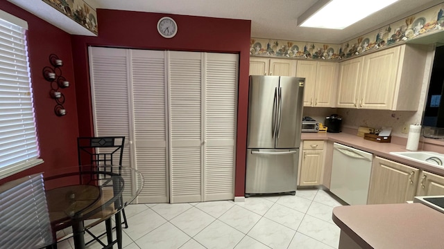 kitchen featuring white dishwasher, light tile patterned flooring, and stainless steel refrigerator