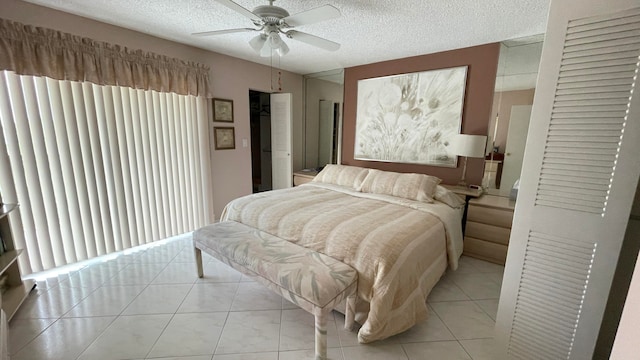 bedroom featuring ceiling fan, light tile patterned flooring, and a textured ceiling