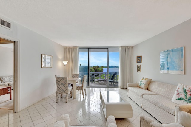 living room featuring a wealth of natural light, light tile patterned flooring, and a wall of windows