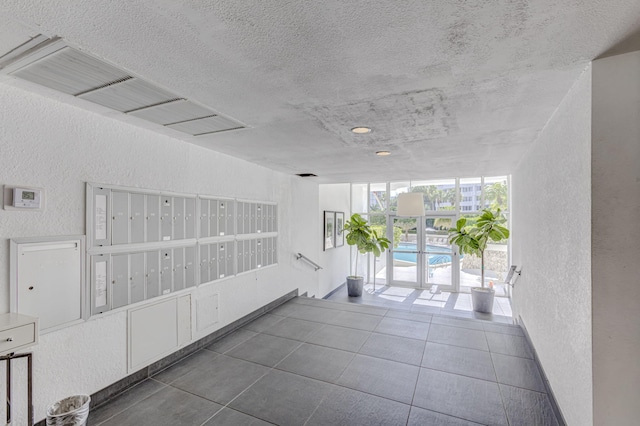 corridor featuring dark tile patterned flooring, mail boxes, and a textured ceiling