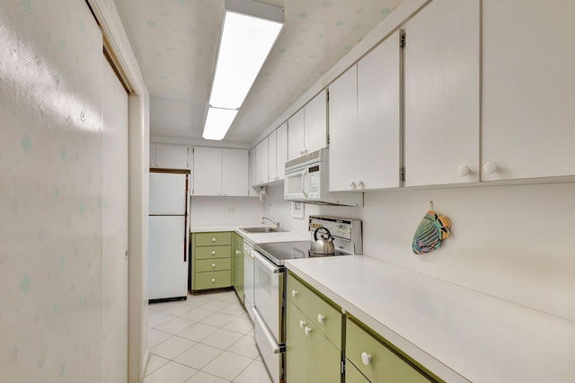 kitchen featuring sink, light tile patterned floors, green cabinets, white appliances, and white cabinets