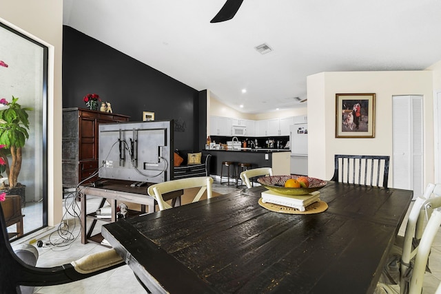 dining area with ceiling fan, light tile patterned floors, and vaulted ceiling