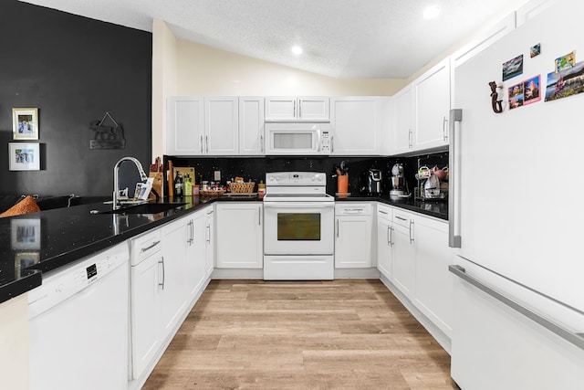 kitchen featuring white cabinetry, sink, backsplash, lofted ceiling, and white appliances