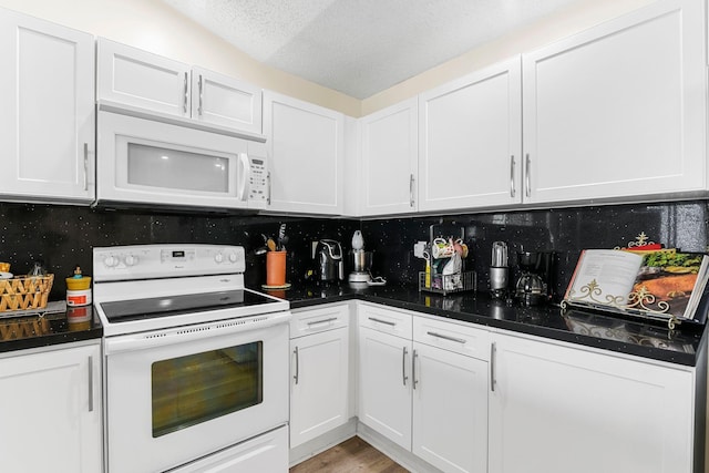 kitchen with white cabinets, decorative backsplash, and white appliances