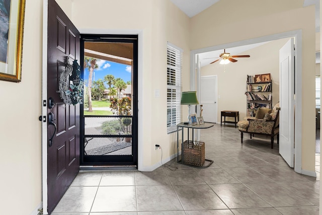 foyer entrance featuring ceiling fan, light tile patterned floors, and vaulted ceiling