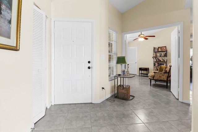 tiled foyer entrance with ceiling fan, a healthy amount of sunlight, and lofted ceiling