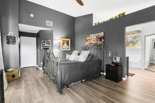 bedroom featuring ensuite bathroom, ceiling fan, a high ceiling, and hardwood / wood-style flooring