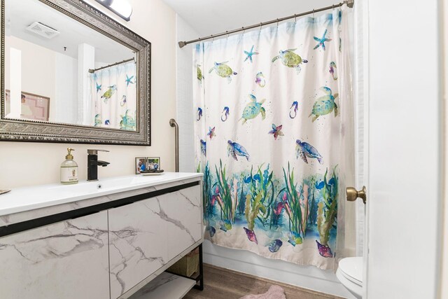 bathroom with hardwood / wood-style floors, vanity, lofted ceiling, toilet, and a textured ceiling