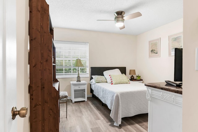 bedroom with a textured ceiling, light wood-type flooring, and ceiling fan