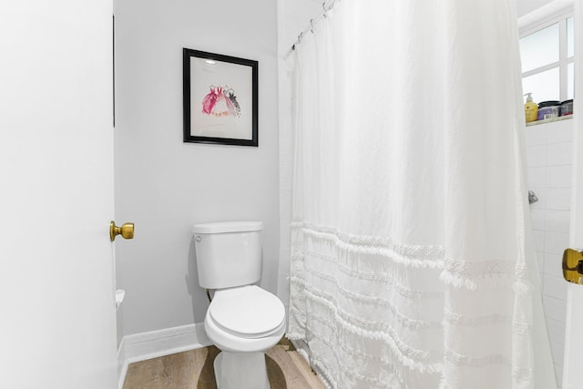 bathroom with a shower with shower curtain, hardwood / wood-style floors, and toilet