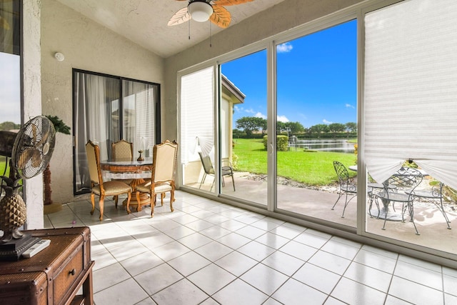 sunroom / solarium with ceiling fan, a water view, and lofted ceiling