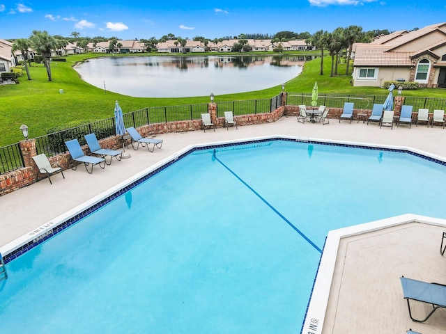 view of swimming pool featuring a yard, a water view, and a patio