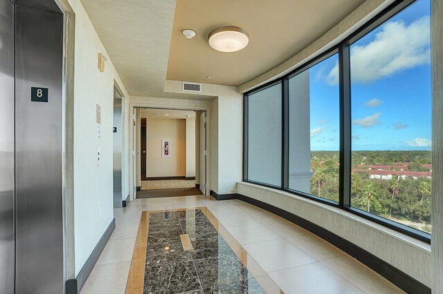 corridor featuring elevator and light tile patterned flooring