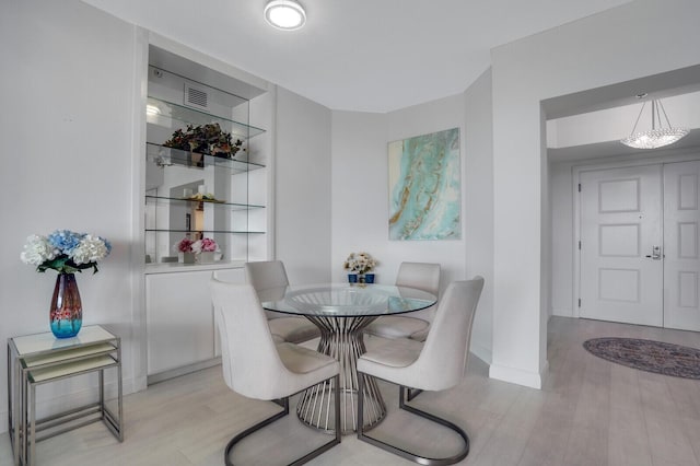 dining area with an inviting chandelier and light hardwood / wood-style flooring