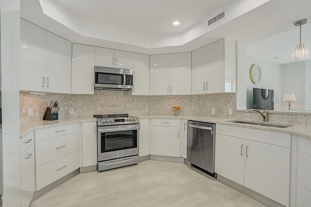 kitchen featuring backsplash, sink, decorative light fixtures, white cabinetry, and stainless steel appliances